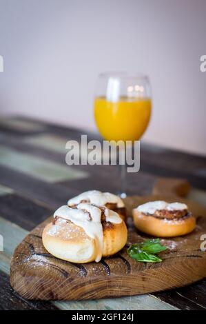 Panini fatti in casa con cannella e un bicchiere di succo di frutta Foto Stock