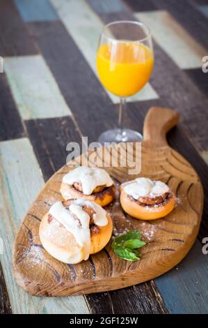 Panini fatti in casa con cannella e un bicchiere di succo di frutta Foto Stock