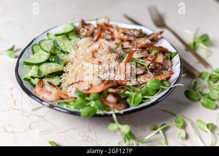 Quinoa con gamberi alla griglia o gamberetti, cetrioli e micro verdi sullo sfondo di marmo vista laterale. Foto Stock