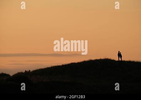 Gower, Swansea, Regno Unito. 22 agosto 2021. Meteo Regno Unito: Riscaldamento. Una coppia gode dell'aria serale più calda sotto i cieli di schiarimento sulla spiaggia di Broughton sulla penisola di Gower. Credit: Gareth Llewelyn/Alamy Foto Stock