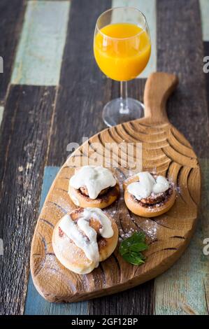 Panini fatti in casa con cannella e un bicchiere di succo di frutta Foto Stock