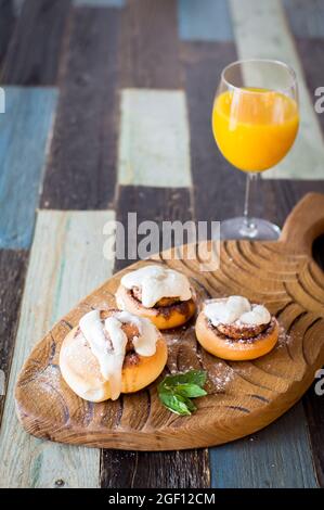 Panini fatti in casa con cannella e un bicchiere di succo di frutta Foto Stock