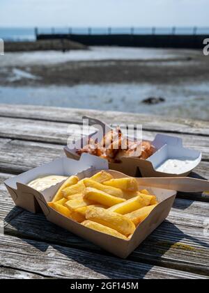 Scatole di carta con patate fritte in bastoncini di olio e pesce serviti all'aperto Foto Stock