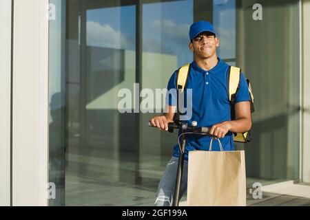 Ritratto dell'uomo di corriere che fa servizio veloce di consegna del cibo usando lo scooter elettrico - consegna concetto di affari di trasporto - fuoco sulla faccia Foto Stock