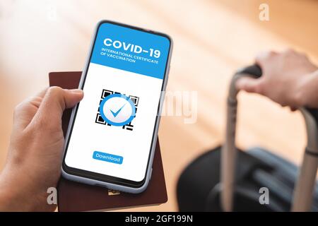 Certificato digitale di vaccinazione covid app - viaggiatore che detiene passaporto di immunità sanitaria sul telefono cellulare all'airpot Foto Stock