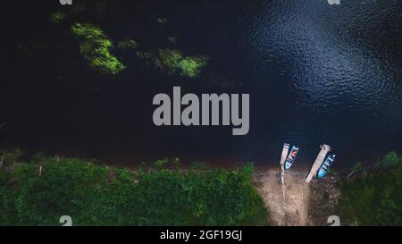 Due barche sono ormeggiate alla riva sulle acque scure di un fiume o di un lago, vista dall'alto. Fauna selvatica, clima planetario. Direzione del turismo, viaggiare Foto Stock