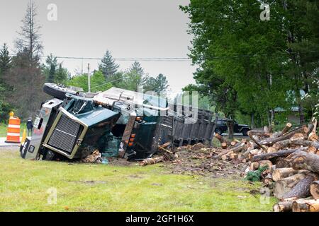 Un incidente di camion di trasporto del ceppo in Hoffmeister, NY USA che coinvolge un camion di taglio rotolare sul suo lato e scaricare un carico di tronchi sulla parte anteriore di una casa. Foto Stock
