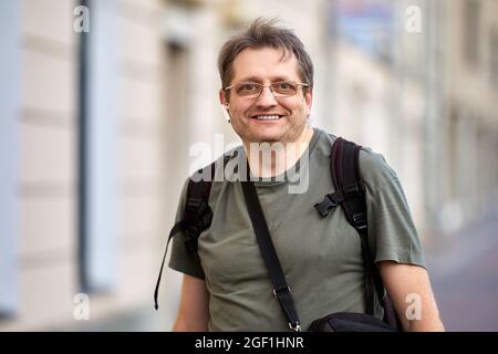 Buon uomo di mezza età con cuffie e zaino all'aperto. Foto Stock
