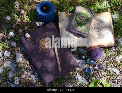 Vita morta con manoscritti e libri di strega, cristallo e candele in giardino. Sfondo esoterico, gotico e occulto, mistico di Halloween e wicca con Foto Stock