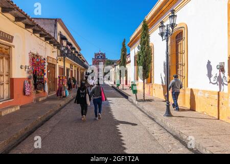 Persone che camminano in una colorata strada in stile coloniale messicano del centro di San Cristobal de las Casas, Chiapas, Messico. Foto Stock