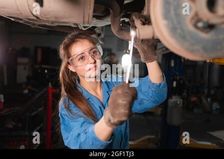 Meccanico che lavora sotto il cofano presso il garage di riparazione Foto Stock