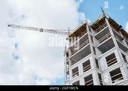Basso angolo di edificio residenziale in costruzione con struttura in mattoni e cemento contro cielo blu, spazio copia Foto Stock