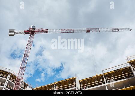 Scatto ad angolo basso dell'edificio residenziale in costruzione con gru da costruzione contro cielo blu, spazio copia Foto Stock
