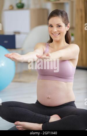 donna incinta medita indoor in posa yoga Foto Stock