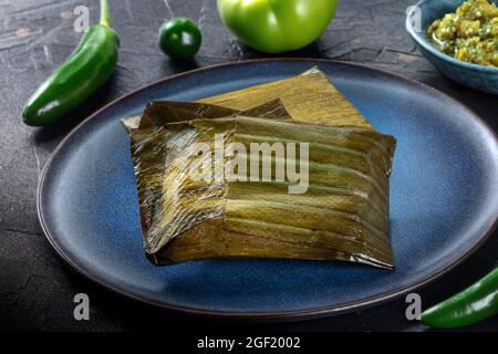 Tamales oaxaquenos, piatto tradizionale della cucina del Messico, vari ripieni avvolti in foglie verdi. Cibo ispanico. Con peperoncini Foto Stock