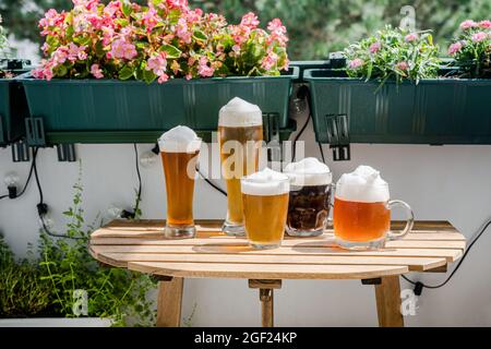 Bicchieri da birra su un tavolo in legno sul balcone verde Foto Stock