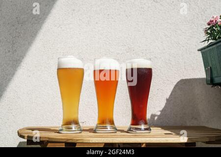 Tre bicchieri di birra su un tavolo in legno all'aperto Foto Stock