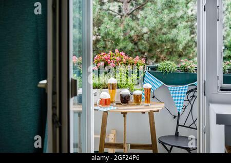 Tavolo in legno con bicchieri da birra sul balcone verde Foto Stock