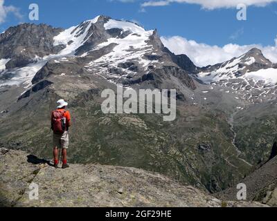 Uomo escursionista con ruckack ammirando la vetta del Gran Paradiso nell'alta Valsavaranche, Valle d'Aosta, Italia Foto Stock