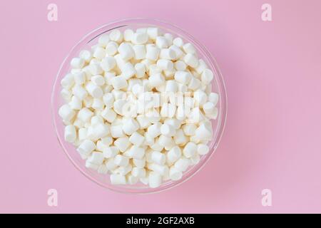 marshmallow bianchi in ciotola su sfondo rosa, vista dall'alto, spazio vuoto per il testo, dessert delizioso Foto Stock