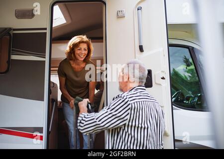 Coppia anziana disimballaggio e parlare in auto, viaggio di vacanza caravan famiglia. Foto Stock