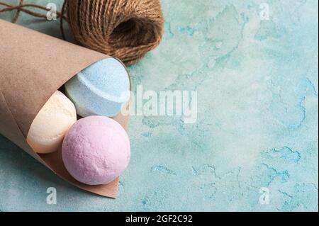 Bombe da bagno blu, vaniglia e fragola nel cono su fondo di cemento turchese Foto Stock