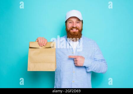 Il deliveryman con espressione felice è pronto a consegnare un pacchetto alimentare Foto Stock