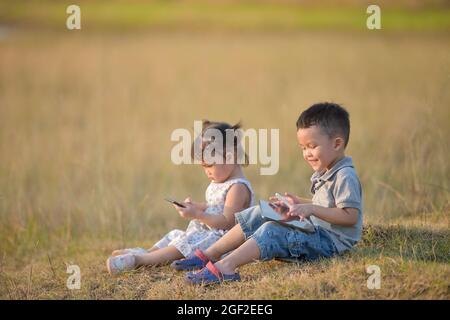 Bambino con tablet.fratelli felici che si trovano all'aperto e giocano con un tablet pc insieme. Foto Stock