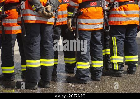 Vigili del fuoco in piedi insieme, strisce retroriflettenti e colori fluorescenti sull'abbigliamento protettivo , Germania Foto Stock