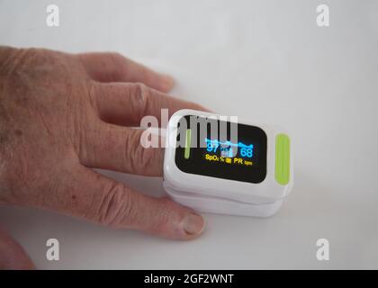 Donna anziana che controlla i livelli di saturazione dell'ossigeno nel sangue e la frequenza del polso utilizzando un ossimetro su un dito Foto Stock