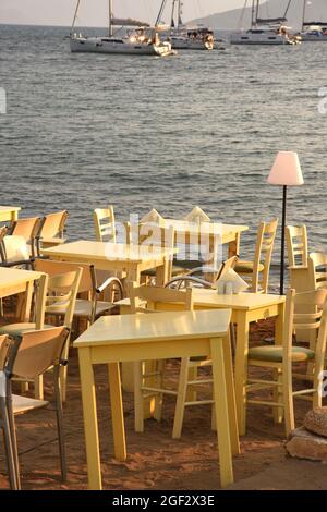 Tavoli allestiti per cena sulla spiaggia al tramonto sul mare a Egina in Grecia Foto Stock