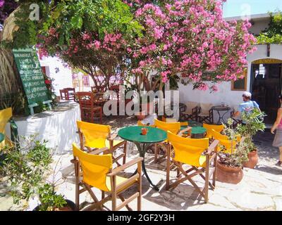 Isola di Amorgos - Grecia - 9 Giugno 2018 : Taverna tradizionale greca colorata in una piazza ombreggiata nella bella, affascinante città vecchia di questa destinazione di vacanza Foto Stock