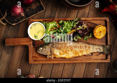 Pesce di trota fritto fatto in casa con salsa e insalata Foto Stock