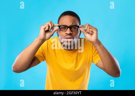 Guy afroamericano con occhi scarsi, sfondo blu Foto Stock