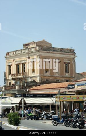 Isola di AEGINA - Grecia - Aprile 30 2017 : scena portuale con gente sul trafficato lungomare. Colorata, tipica vista del porto greco. Scatto verticale. Foto Stock