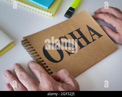 L'uomo legge la guida OSHA che è sul tavolo. Foto Stock