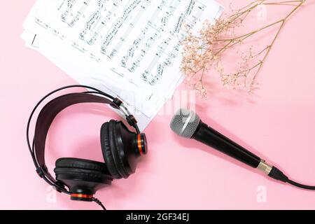 Vista dall'alto di una disposizione piatta di note musicali, microfono e cuffie su sfondo rosa Foto Stock