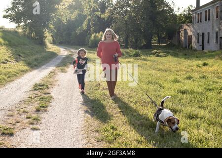 Donna anziana alla moda e la sua bambina godendo una passeggiata in campagna con il loro cane beagle - nonna e nipote felici insieme Foto Stock