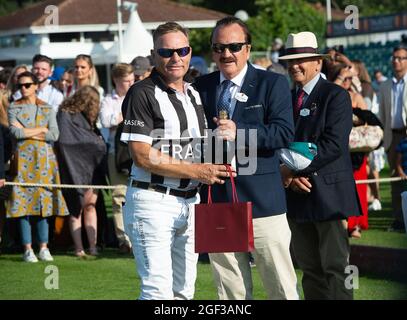 Egham, Surrey, Regno Unito. 22 agosto 2021. L'umpire della polo Jason Dixon riceve il suo regalo Cartier e lo champagne da John Collins CEO e fondatore di Talacrest dopo aver ricevuto la finale della Coppa del campionato del Principe di Galles di Talacrest al Guards Polo Club. Credit: Maureen McLean/Alamy Foto Stock