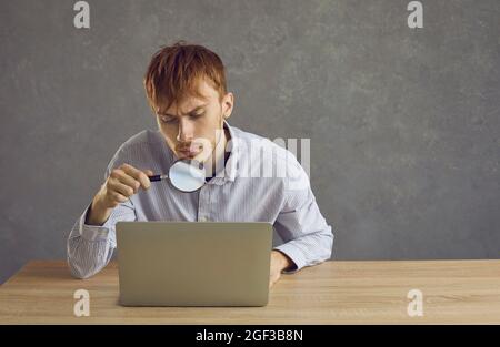 Giovane uomo bello guarda attraverso una lente d'ingrandimento Foto Stock