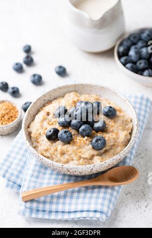 Ciotola di farina d'avena con mirtilli e semi di lino su tessuto blu. Colazione sana Foto Stock
