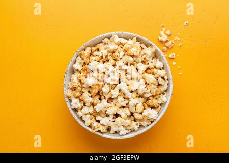 Ciotola di popcorn isolato su sfondo giallo, vista dall'alto Foto Stock