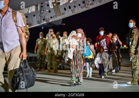 Sigonella, Italia. 22 agosto 2021. Gli evacuati afghani sbarcano da un aereo della U.S. Air Force C-17 Globemaster III dopo l'arrivo alla Stazione aeronavale di Sigonella il 22 agosto 2021 a Sigonella, Italia. NAS Sigonella fornisce alloggio temporaneo per gli evacuati dall'Afghanistan come parte dell'operazione Rifugi Alleati. Credit: Planetpix/Alamy Live News Foto Stock