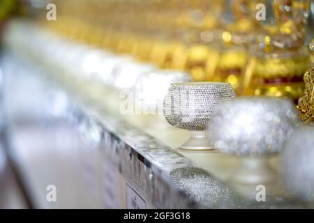 Ciotola di Buddha con glitter e scintillanti allmi sono decorate con diamante di plastica. Si posano sul bancone del Tempio Thailandese. Foto Stock