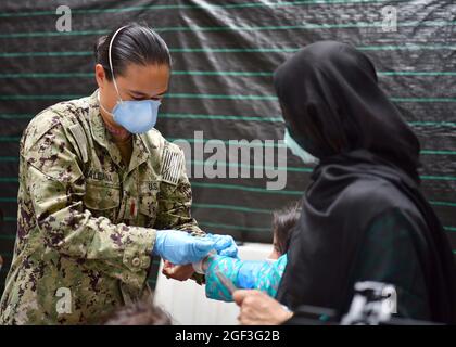 Sigonella, Italia. 22 agosto 2021. U.S. Navy Ens. Galgana assiste una famiglia afghana evacuata da Kabul, è assistito dopo l'arrivo alla Stazione Navale aerea di Sigonella 22 agosto 2021 a Sigonella, Italia. NAS Sigonella fornisce alloggio temporaneo per gli evacuati dall'Afghanistan come parte dell'operazione Rifugi Alleati. Credit: Planetpix/Alamy Live News Foto Stock