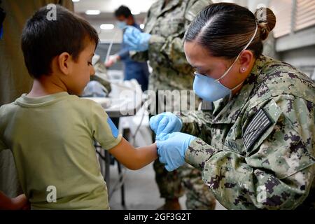 Sigonella, Italia. 22 agosto 2021. Un ragazzo afghano evacuato da Kabul, è assistito dopo l'arrivo alla Stazione aeronavale di Sigonella il 22 agosto 2021 a Sigonella, Italia. NAS Sigonella fornisce alloggio temporaneo per gli evacuati dall'Afghanistan come parte dell'operazione Rifugi Alleati. Credit: Planetpix/Alamy Live News Foto Stock