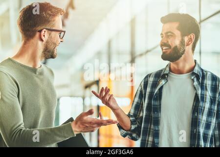Due giovani studenti maschi che parlano di qualcosa nel corridoio Foto Stock