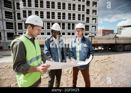 Gruppo di ingegneri diversi che discutono di piani di cantiere, spazio di copia Foto Stock