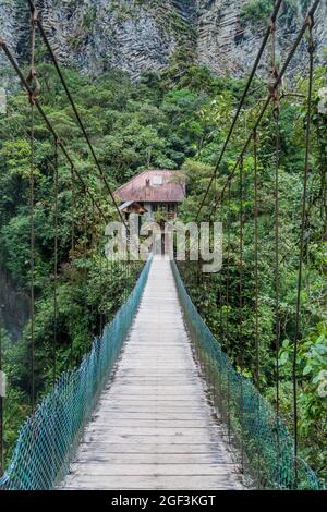 Ponte di Suspnsion che attraversa la cascata Pailon del Diablo (Cauldron del Diavolo) vicino alla città di Banos, Ecuador Foto Stock