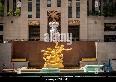 I visitatori di Rockefeller Plaza vedono la "CONDIVISIONE" dell'artista KAWS esposta come parte dell'arte pubblica del Rockefeller Center, vista sopra "Prometheus" di Paul Manship, mercoledì 11 agosto 2021. La scultura in bronzo alta 18 metri, che mostra motivi di carattere cartoon utilizzati dall'artista, sarà in mostra fino a ottobre. (© Richard B. Levine) Foto Stock